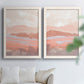 Set of two white barnwood framed canvas prints depicting low mountain silhouettes, horizontal bands, and muted atmospheric color arranged across two complementary compositions above a sofa in a bright living space.