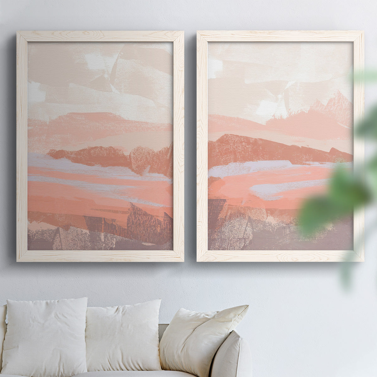 Set of two white barnwood framed canvas prints depicting low mountain silhouettes, horizontal bands, and muted atmospheric color arranged across two complementary compositions above a sofa in a bright living space.