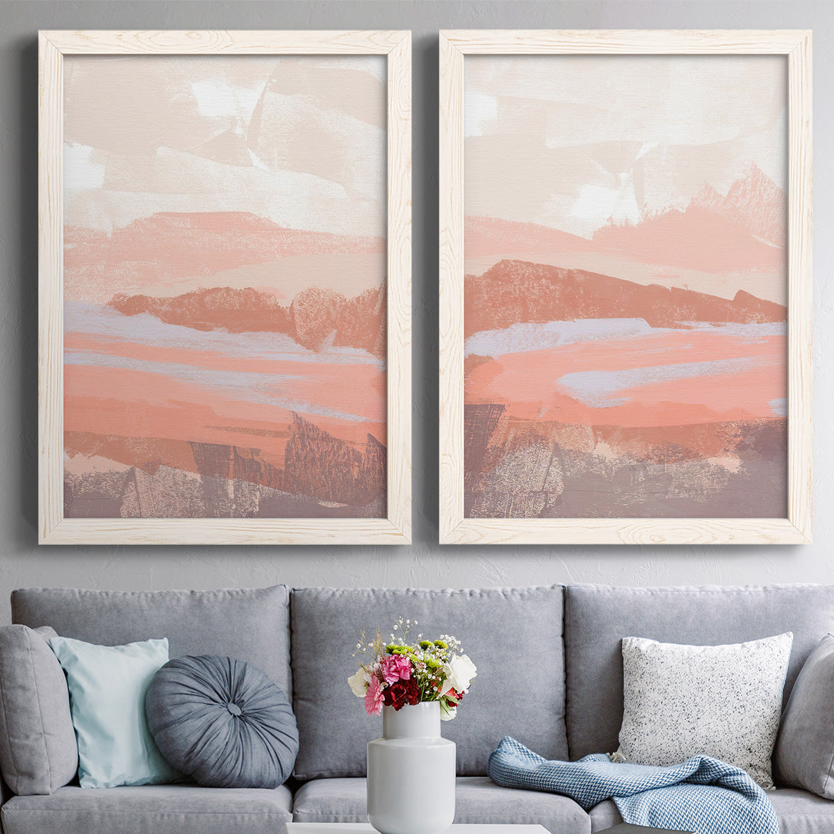 Set of two white barnwood framed canvas prints depicting paired modern abstract landscapes with low mountain silhouettes, horizontal bands, and muted atmospheric color above a sofa in a contemporary living room.