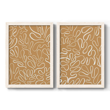 Set of two white barnwood framed canvas prints featuring two graphic botanical pattern abstracts featuring continuous white organic lines over solid ochre and blush fields.