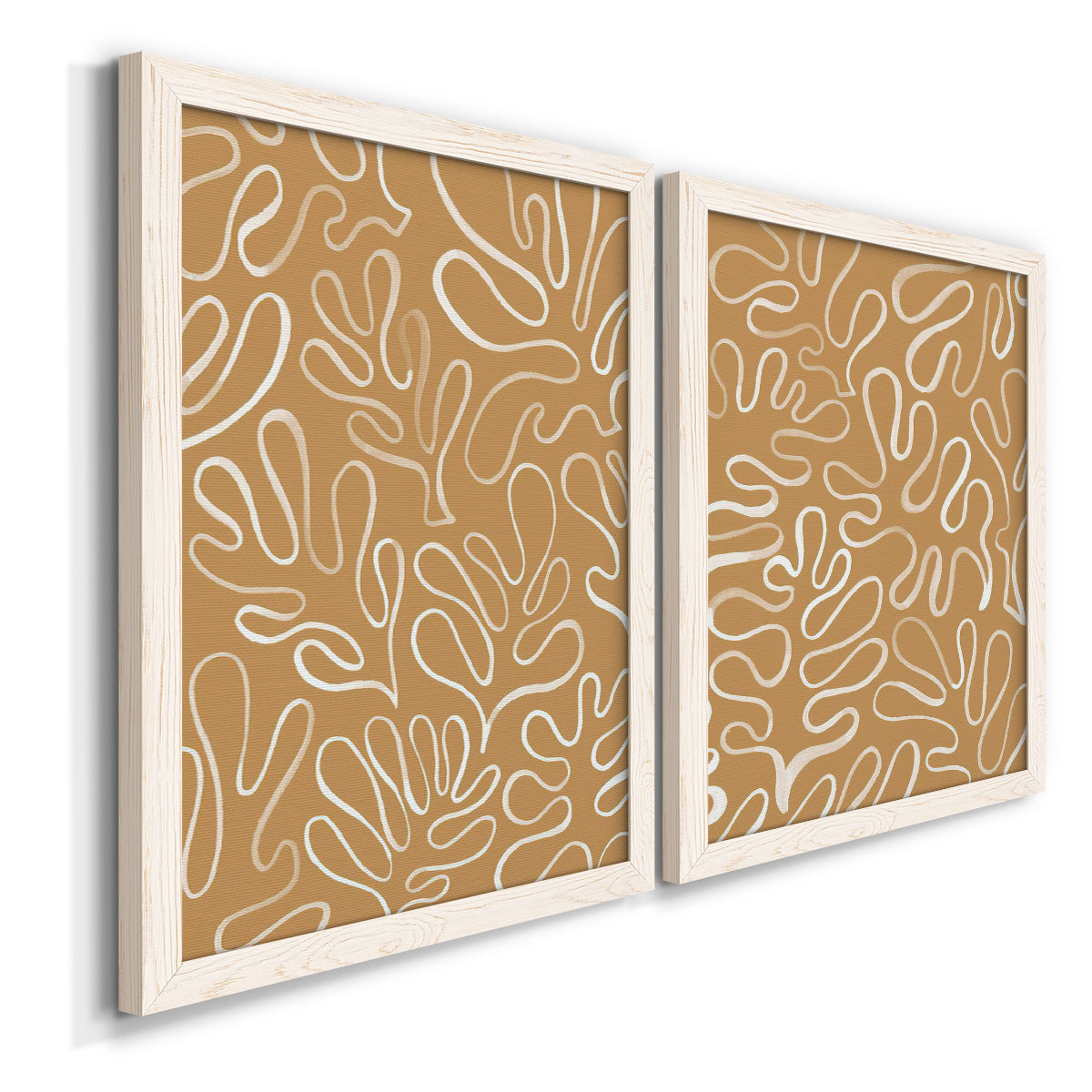 Angled view of a set of two white barnwood framed canvas prints featuring two graphic botanical pattern abstracts featuring continuous white organic lines over solid ochre and blush fields.