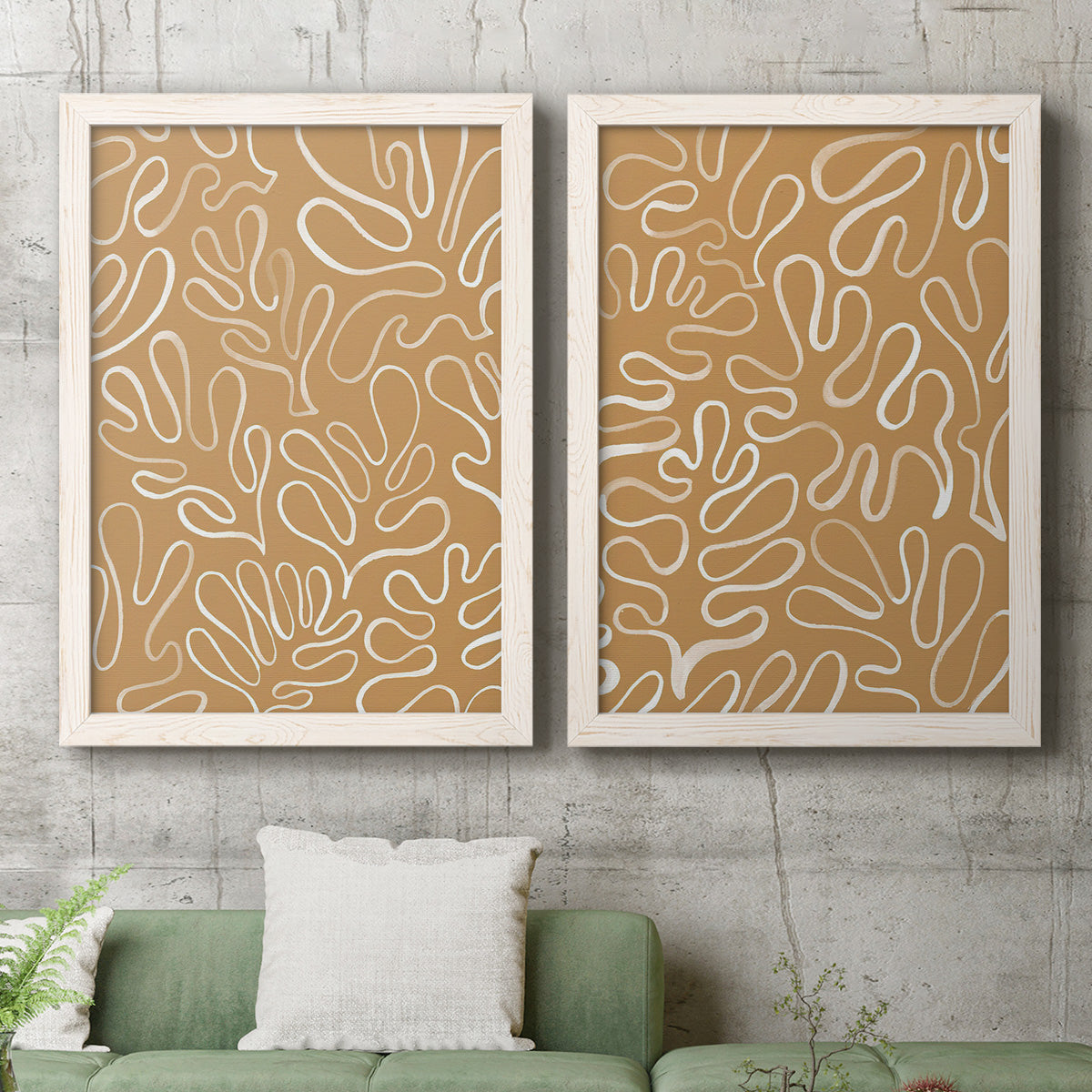 Set of two white barnwood framed canvas prints depicting a coordinated art pair of continuous white organic lines over solid ochre and blush fields rendered as graphic botanical pattern abstracts above a sofa in a modern living room.