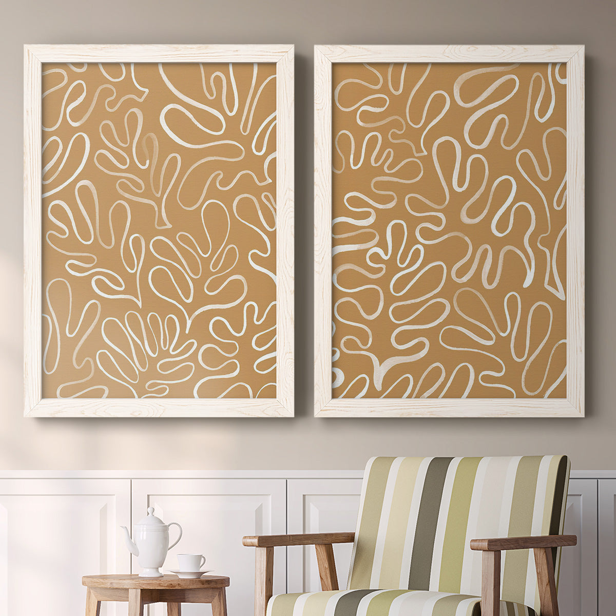 Set of two white barnwood framed canvas prints depicting two graphic botanical pattern abstracts featuring continuous white organic lines over solid ochre and blush fields above a sideboard in a cozy sitting room.