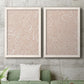 Set of two white barnwood framed canvas prints depicting a coordinated art pair of continuous white organic lines over solid ochre and blush fields rendered as graphic botanical pattern abstracts above a sofa in a modern living room.