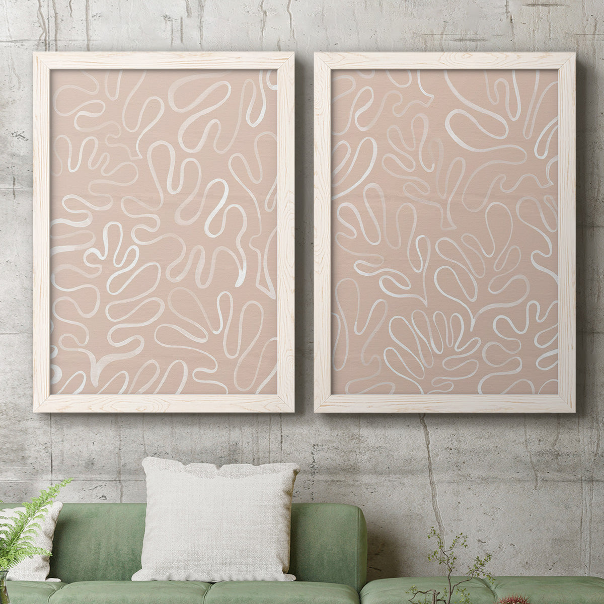 Set of two white barnwood framed canvas prints depicting a coordinated art pair of continuous white organic lines over solid ochre and blush fields rendered as graphic botanical pattern abstracts above a sofa in a modern living room.