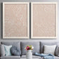 Set of two white barnwood framed canvas prints depicting paired graphic botanical pattern abstracts with leaf-like contours, flat warm backgrounds, and repeated flowing shapes above a sofa in a contemporary living room.