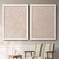 Set of two white barnwood framed canvas prints depicting two graphic botanical pattern abstracts featuring continuous white organic lines over solid ochre and blush fields above a sideboard in a cozy sitting room.