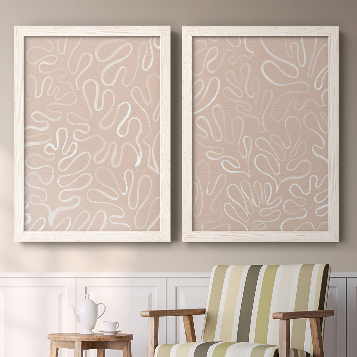 Set of two white barnwood framed canvas prints depicting two graphic botanical pattern abstracts featuring continuous white organic lines over solid ochre and blush fields above a sideboard in a cozy sitting room.