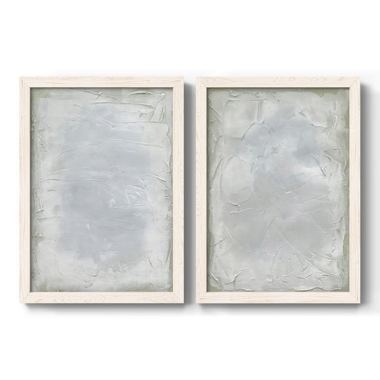 Set of two white barnwood framed canvas prints featuring two quiet textural abstracts featuring layered white and silver-gray painted surfaces.