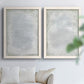 Set of two white barnwood framed canvas prints depicting soft palette-knife marks, cloudy transitions, and nearly monochrome fields arranged across two complementary compositions above a sofa in a bright living space.