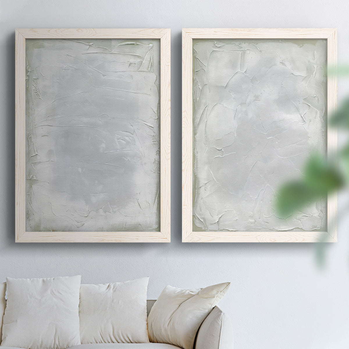Set of two white barnwood framed canvas prints depicting soft palette-knife marks, cloudy transitions, and nearly monochrome fields arranged across two complementary compositions above a sofa in a bright living space.