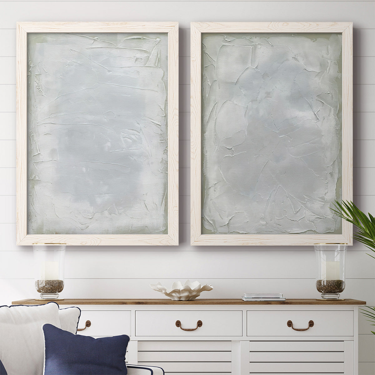 Set of two white barnwood framed canvas prints depicting a coordinated art pair of layered white and silver-gray painted surfaces rendered as quiet textural abstracts above a dining room sideboard.