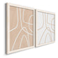 Angled view of a set of two white barnwood framed canvas prints featuring two minimalist line abstracts featuring single continuous tan lines forming oversized organic curves.