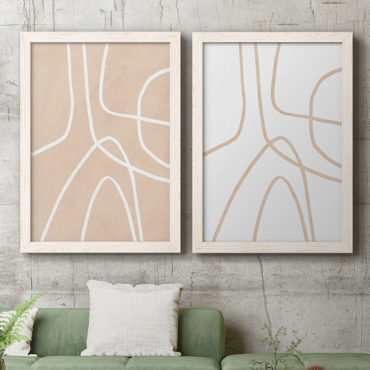 Set of two white barnwood framed canvas prints depicting a coordinated art pair of single continuous tan lines forming oversized organic curves rendered as minimalist line abstracts above a sofa in a modern living room.