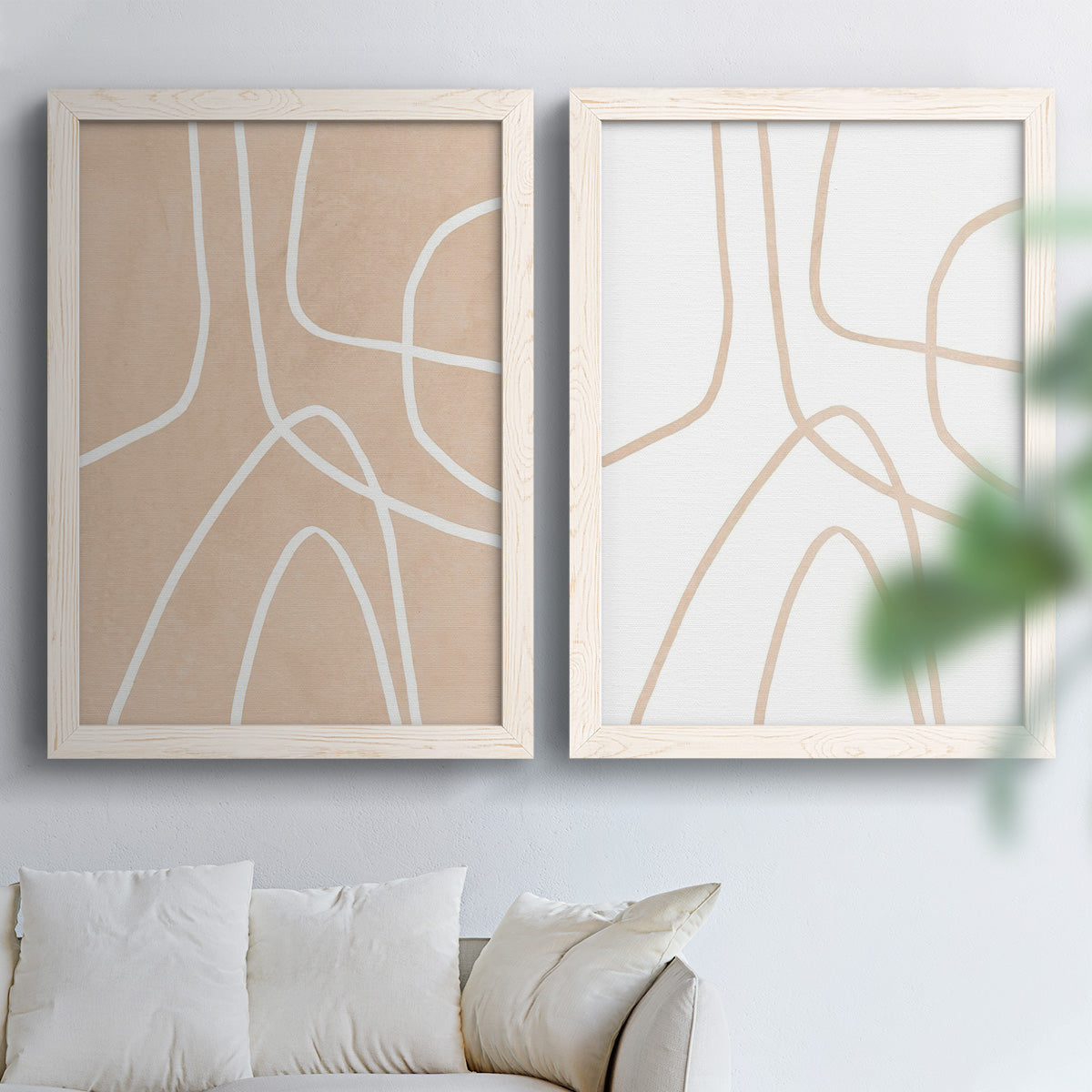 Set of two white barnwood framed canvas prints depicting warm beige grounds, white contour paths, and quiet negative space arranged across two complementary compositions above a sofa in a bright living space.