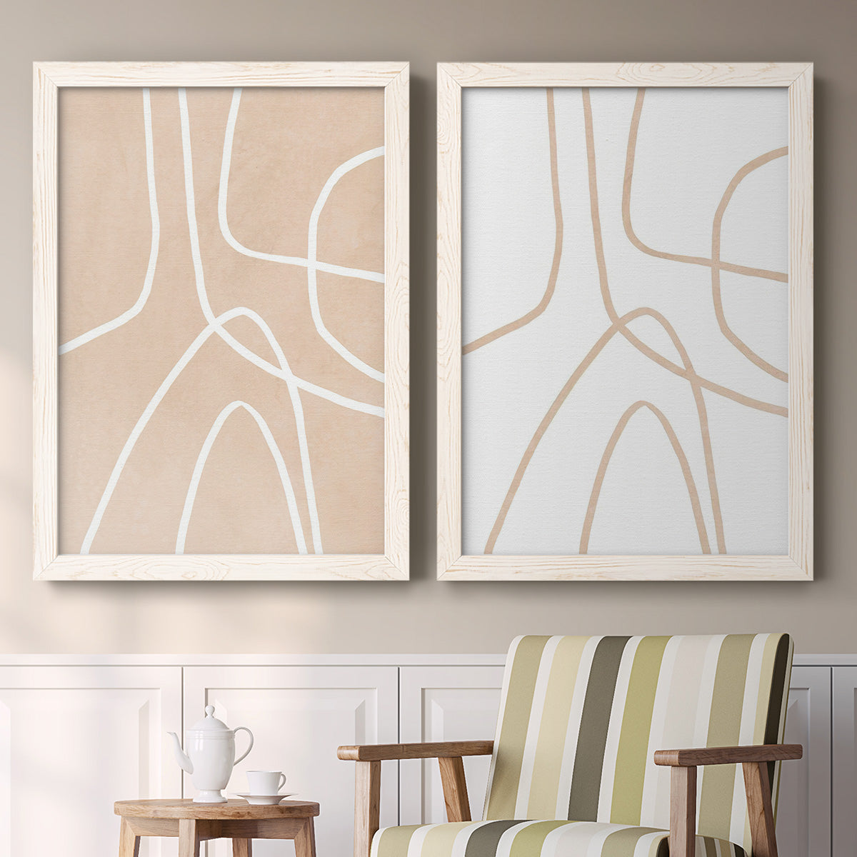 Set of two white barnwood framed canvas prints depicting two minimalist line abstracts featuring single continuous tan lines forming oversized organic curves above a sideboard in a cozy sitting room.