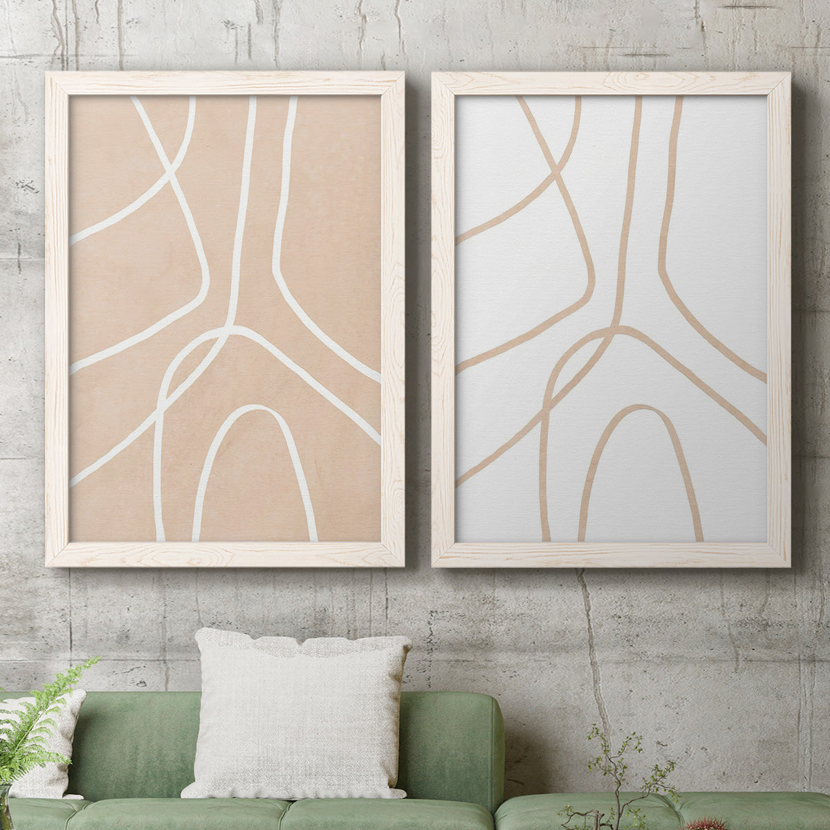 Set of two white barnwood framed canvas prints depicting a coordinated art pair of single continuous tan lines forming oversized organic curves rendered as minimalist line abstracts above a sofa in a modern living room.