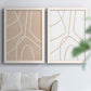 Set of two white barnwood framed canvas prints depicting warm beige grounds, white contour paths, and quiet negative space arranged across two complementary compositions above a sofa in a bright living space.