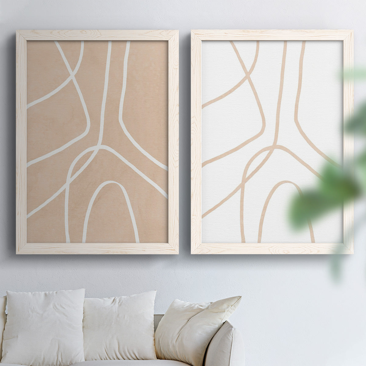 Set of two white barnwood framed canvas prints depicting warm beige grounds, white contour paths, and quiet negative space arranged across two complementary compositions above a sofa in a bright living space.