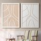 Set of two white barnwood framed canvas prints depicting two minimalist line abstracts featuring single continuous tan lines forming oversized organic curves above a sideboard in a cozy sitting room.