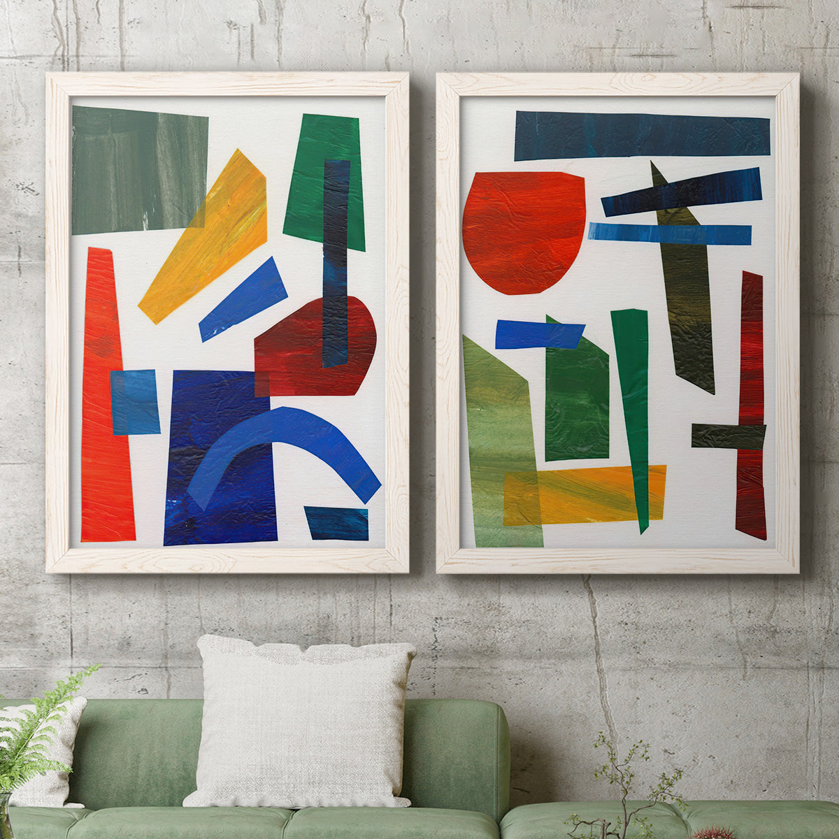 Set of two white barnwood framed canvas prints depicting a coordinated art pair of bold red blue green yellow and black geometric forms rendered as mid-century graphic abstracts above a sofa in a modern living room.