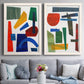 Set of two white barnwood framed canvas prints depicting paired mid-century graphic abstracts with flat rectangles arcs and angled bars on cream grounds above a sofa in a contemporary living room.