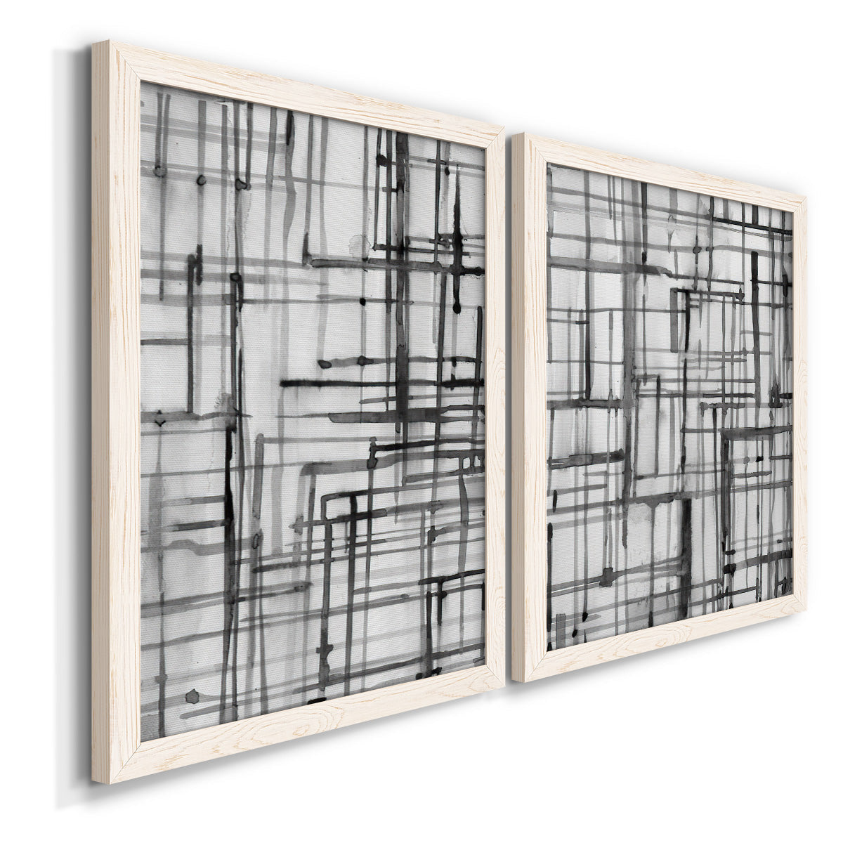 Angled view of a set of two white barnwood framed canvas prints featuring two monochrome geometric abstracts featuring layered black linear grids.