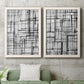 Set of two white barnwood framed canvas prints depicting a coordinated art pair of layered black linear grids rendered as monochrome geometric abstracts above a sofa in a modern living room.