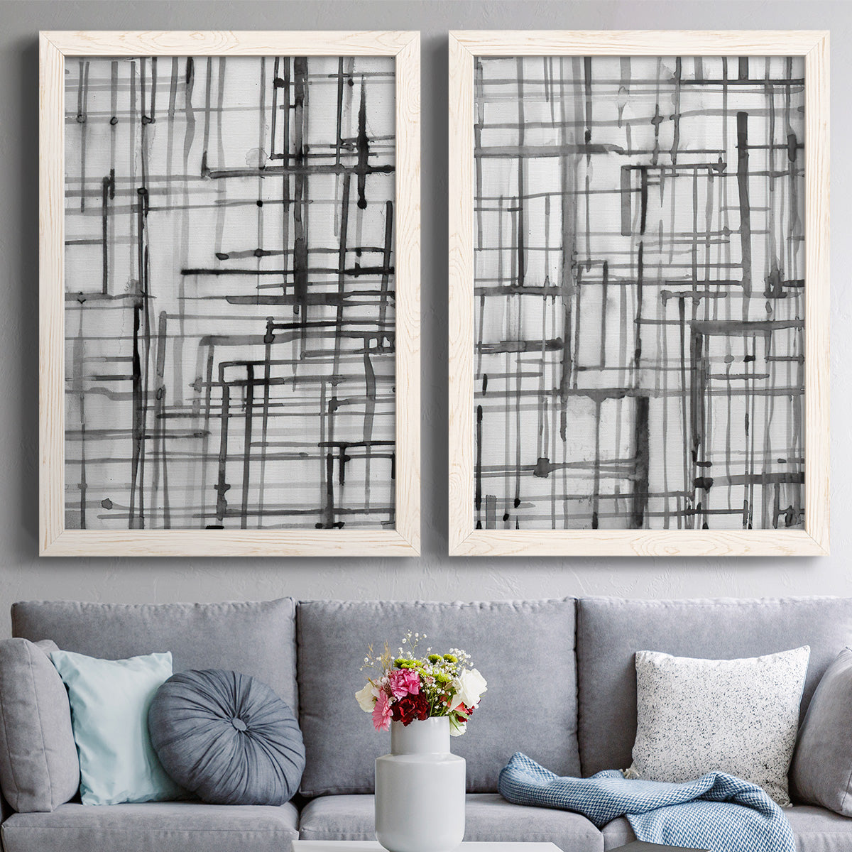 Set of two white barnwood framed canvas prints depicting paired monochrome geometric abstracts with overlapping rectangles, hand-drawn verticals, and transparent gray intersections above a sofa in a contemporary living room.