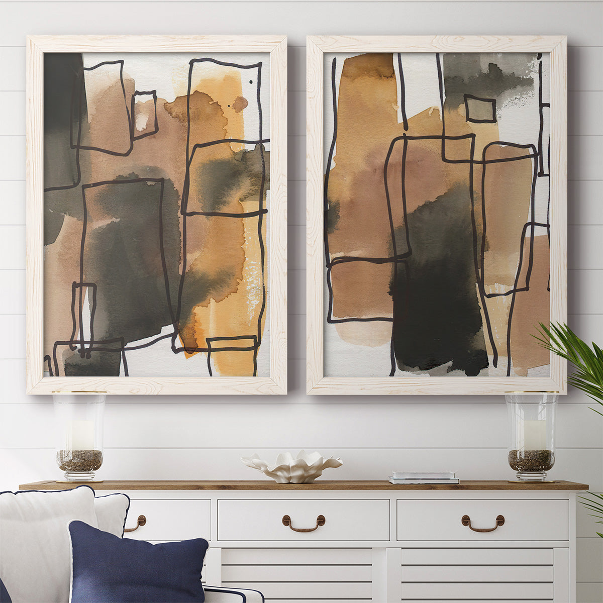 Set of two white barnwood framed canvas prints depicting a coordinated art pair of earthy watercolor blocks crossed by black contour lines rendered as retro geometric abstracts above a dining room sideboard.