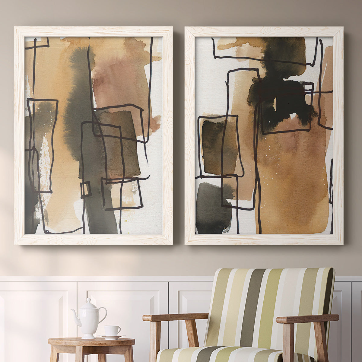 Set of two white barnwood framed canvas prints depicting two retro geometric abstracts featuring earthy watercolor blocks crossed by black contour lines above a sideboard in a cozy sitting room.