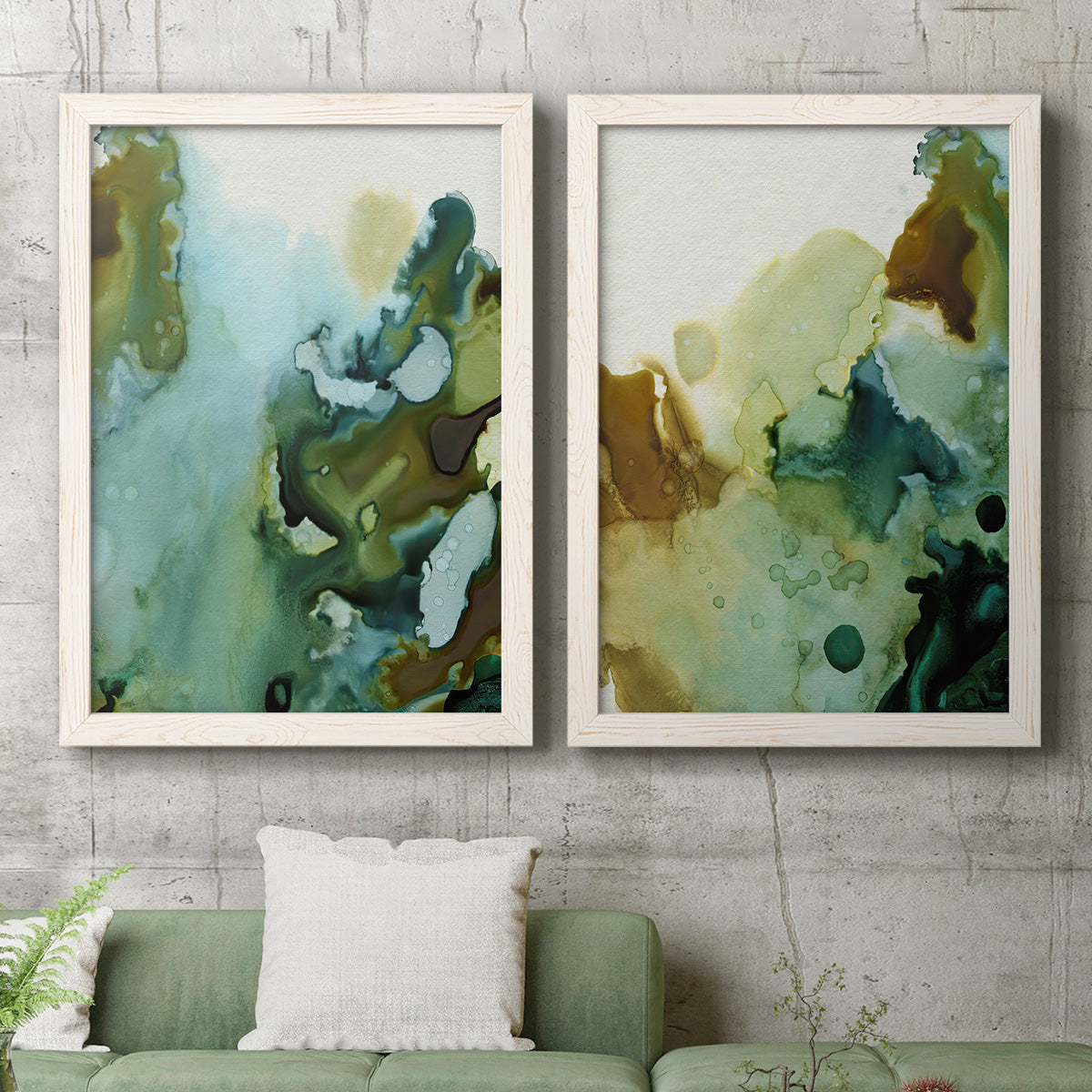Set of two white barnwood framed canvas prints depicting a coordinated art pair of fluid green blue and earthy brown ink pools rendered as organic watercolor abstracts above a sofa in a modern living room.