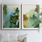 Set of two white barnwood framed canvas prints depicting translucent washes, dark branching edges, and mineral-like blooms arranged across two complementary compositions above a sofa in a bright living space.