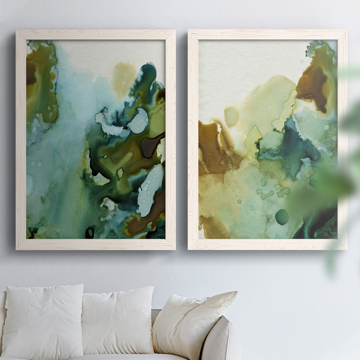 Set of two white barnwood framed canvas prints depicting translucent washes, dark branching edges, and mineral-like blooms arranged across two complementary compositions above a sofa in a bright living space.