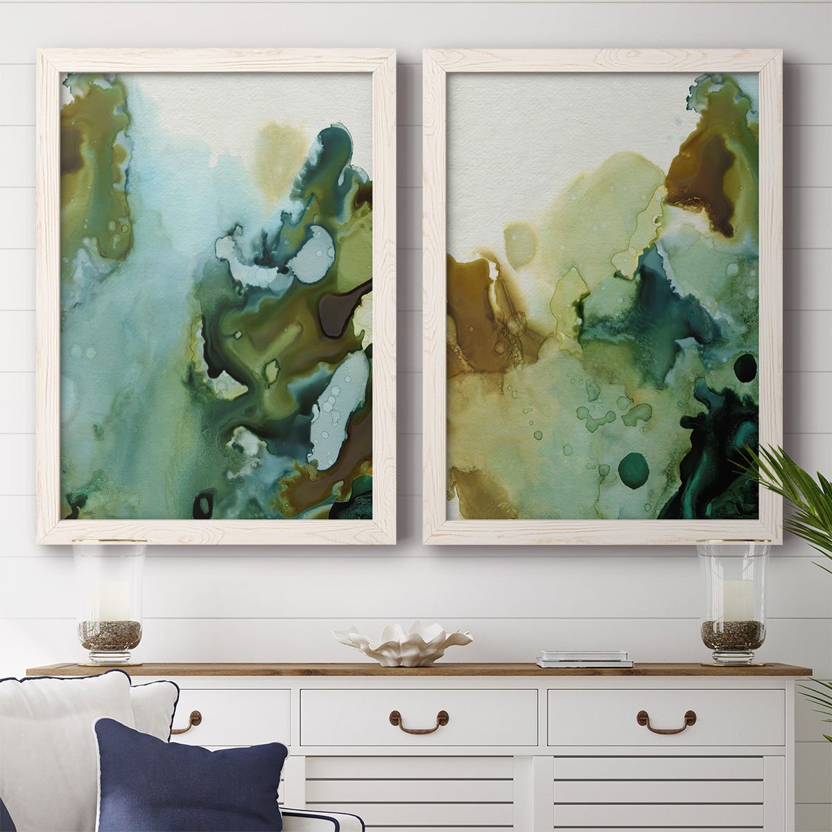 Set of two white barnwood framed canvas prints depicting a coordinated art pair of fluid green blue and earthy brown ink pools rendered as organic watercolor abstracts above a dining room sideboard.