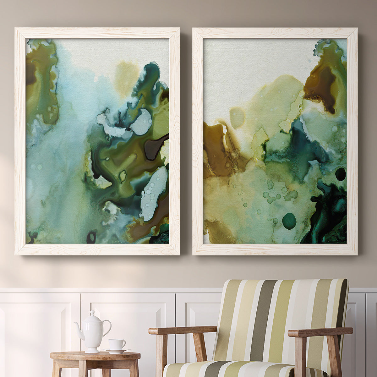Set of two white barnwood framed canvas prints depicting two organic watercolor abstracts featuring fluid green blue and earthy brown ink pools above a sideboard in a cozy sitting room.