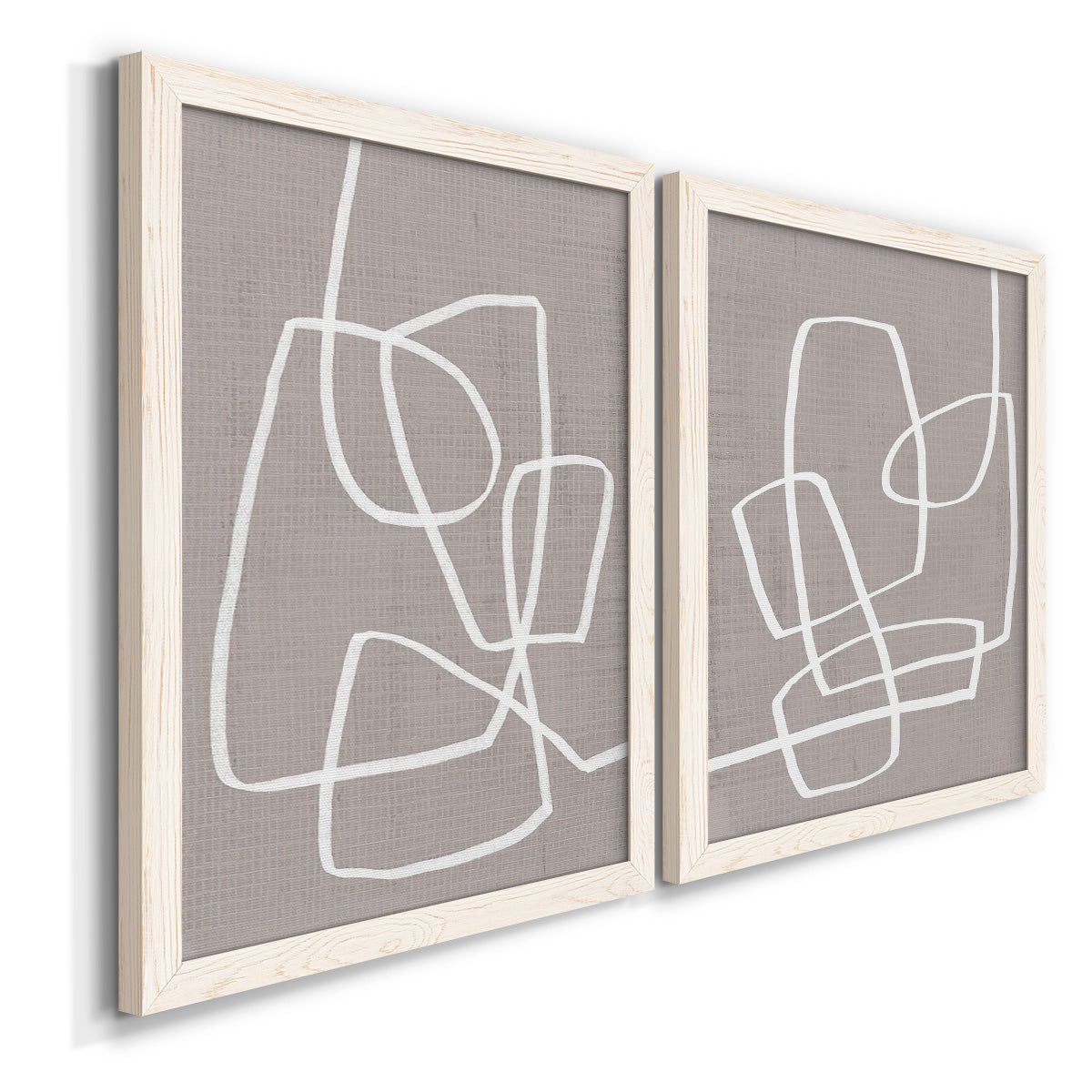 Angled view of a set of two white barnwood framed canvas prints featuring two minimalist geometric line art featuring overlapping white continuous-line loops on taupe.