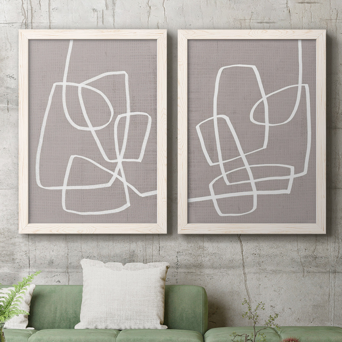 Set of two white barnwood framed canvas prints depicting a coordinated art pair of overlapping white continuous-line loops on taupe rendered as minimalist geometric line art above a sofa in a modern living room.