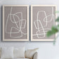 Set of two white barnwood framed canvas prints depicting rounded rectangular contours, soft gray grounds, and sparse composition arranged across two complementary compositions above a sofa in a bright living space.