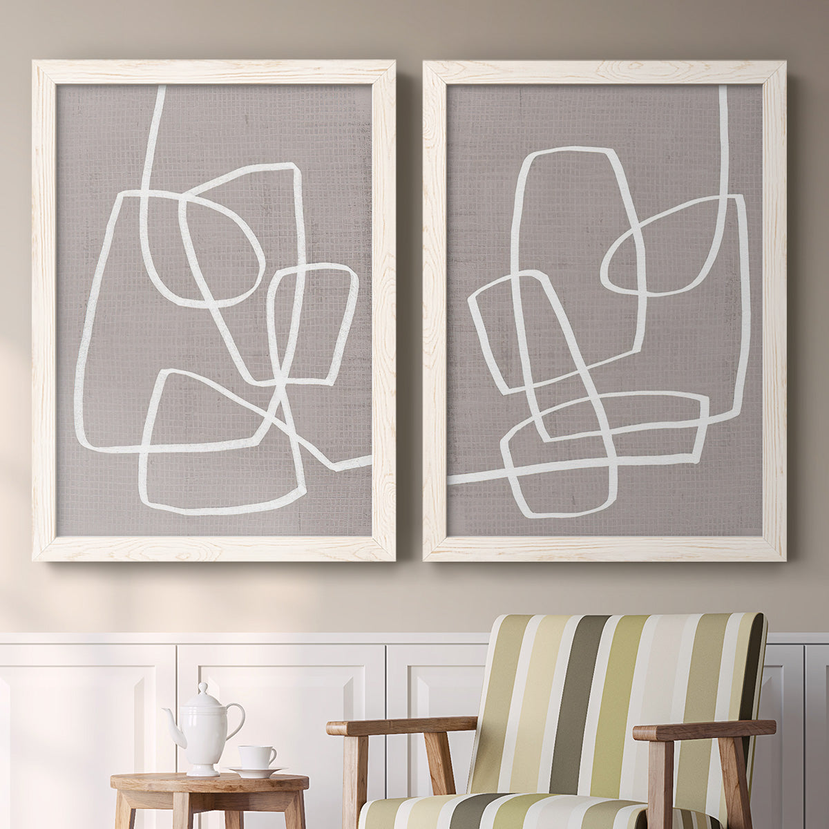 Set of two white barnwood framed canvas prints depicting two minimalist geometric line art featuring overlapping white continuous-line loops on taupe above a sideboard in a cozy sitting room.