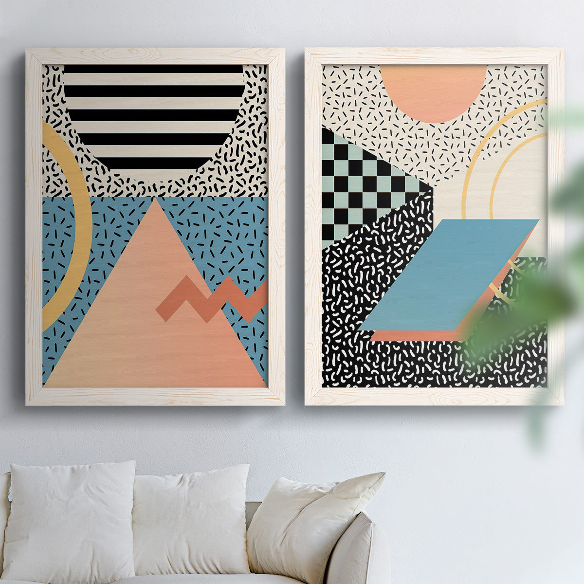 Set of two white barnwood framed canvas prints depicting checkerboards stripes squiggles peach blue black and mint shapes arranged across two complementary compositions above a sofa in a bright living space.