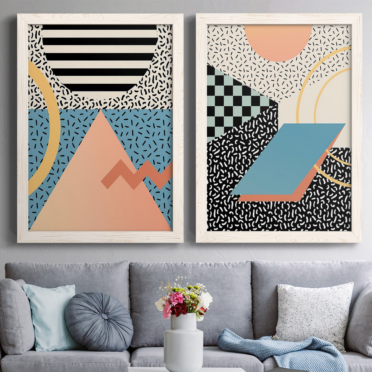 Set of two white barnwood framed canvas prints depicting paired retro graphic abstracts with checkerboards stripes squiggles peach blue black and mint shapes above a sofa in a contemporary living room.