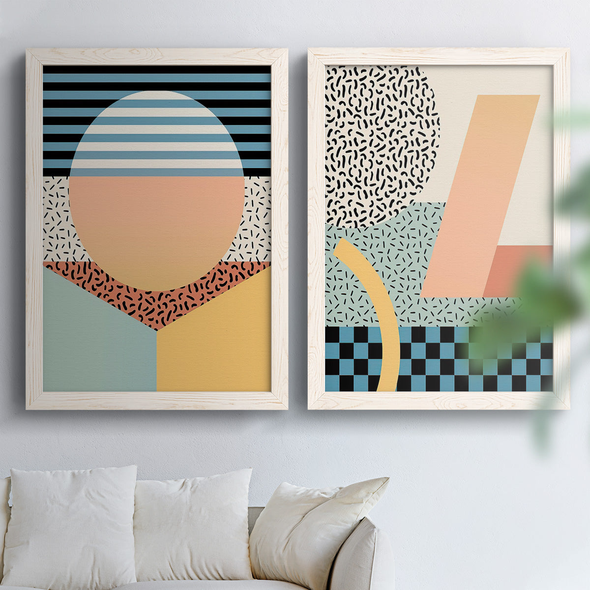 Set of two white barnwood framed canvas prints depicting checkerboards stripes squiggles peach blue black and mint shapes arranged across two complementary compositions above a sofa in a bright living space.