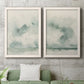 Set of two white barnwood framed canvas prints depicting a serene coastal pair of hazy skies distant shorelines and soft sage green washes above a sofa in a modern living room.