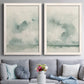 Set of two white barnwood framed canvas prints depicting soft coastal landscapes with cloudlike brushwork still water and a muted foggy palette above a sofa in a contemporary living room.