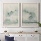 Set of two white barnwood framed canvas prints depicting a serene coastal pair of hazy skies distant shorelines and soft sage green washes above a dining room sideboard.