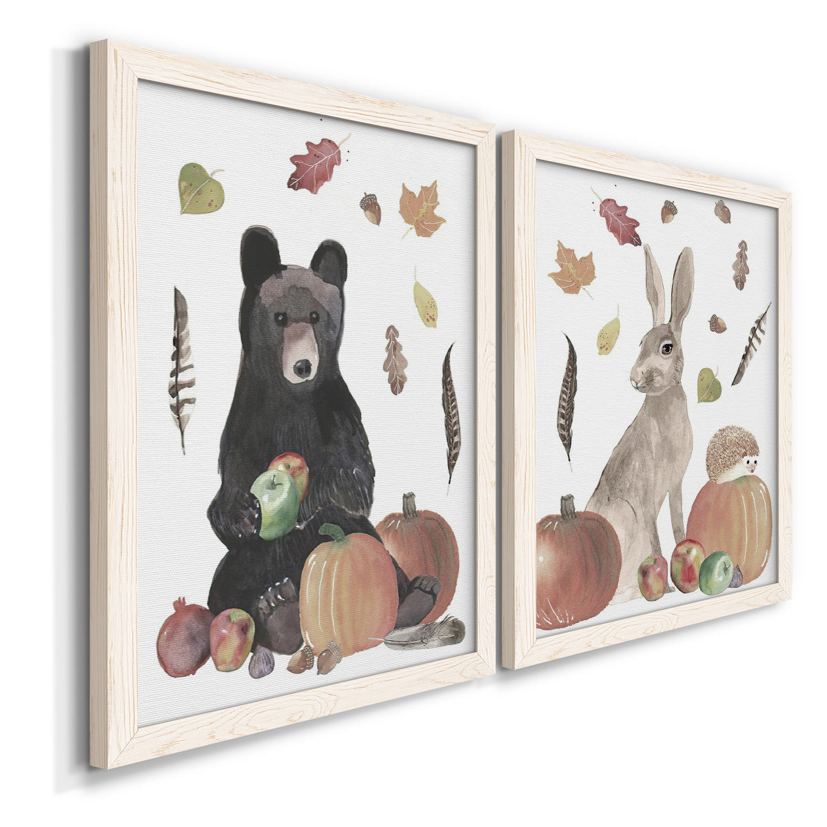 Angled view of a set of two white barnwood framed canvas prints featuring a watercolor woodland animal pair with a bear rabbit hedgehog pumpkins fruit acorns and falling leaves.