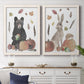 Set of two white barnwood framed canvas prints depicting two whimsical autumn illustrations of forest animals gathered among pumpkins apples feathers and seasonal foliage above a dining room sideboard.