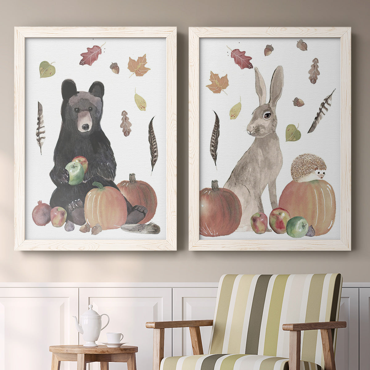 Set of two white barnwood framed canvas prints depicting a watercolor woodland animal pair with a bear rabbit hedgehog pumpkins fruit acorns and falling leaves above a sideboard in a cozy sitting room.