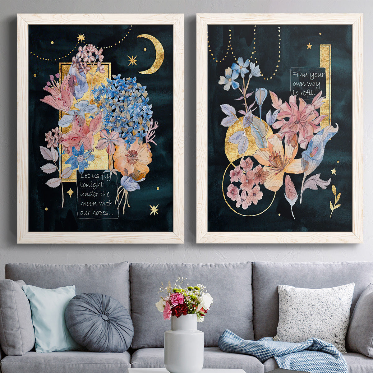 Set of two white barnwood framed canvas prints depicting paired whimsical floral collages with moons stars hanging jewels colorful blossoms and hand-lettered phrases above a sofa in a contemporary living room.